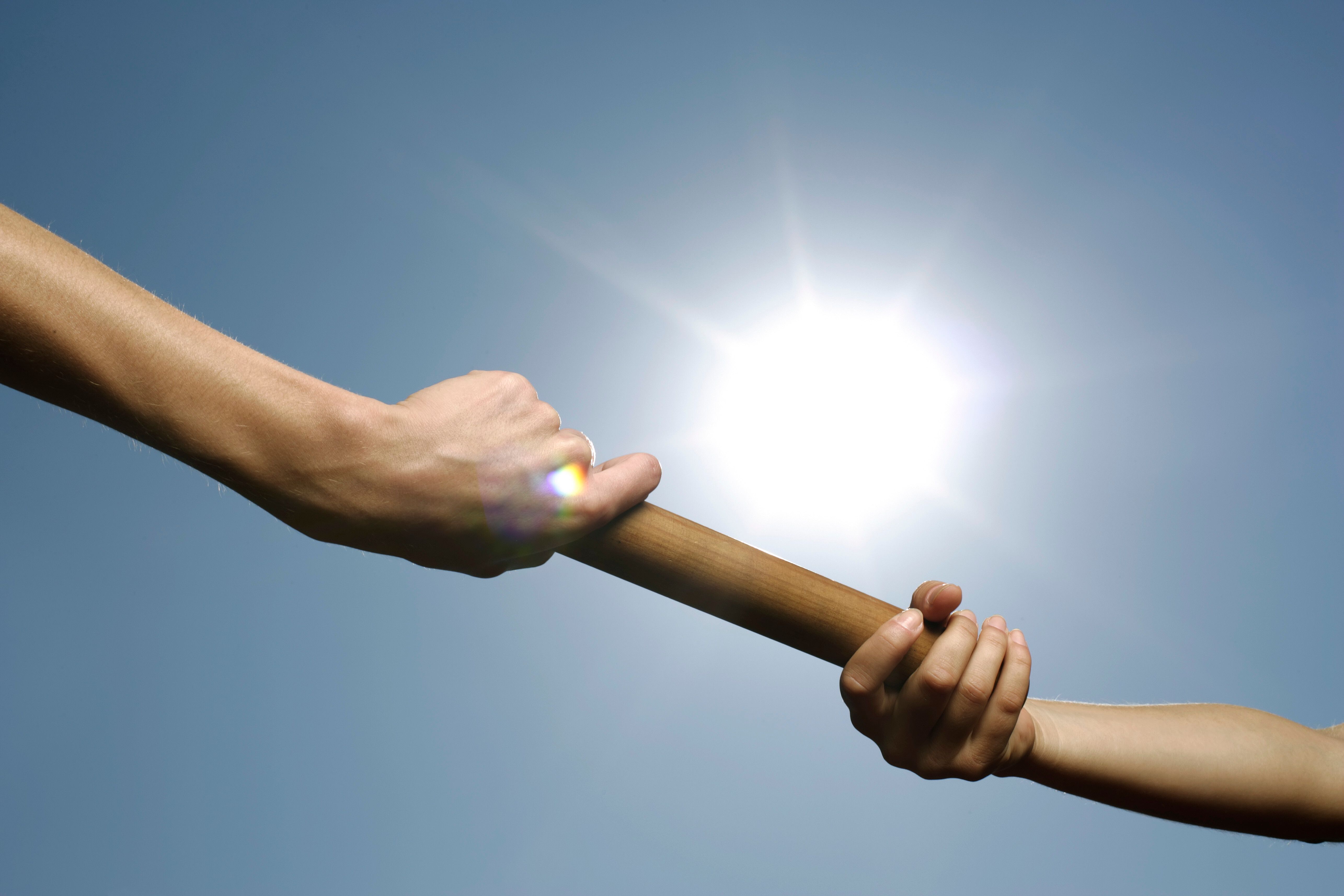 Close-up of two runners passing a relay baton during a race