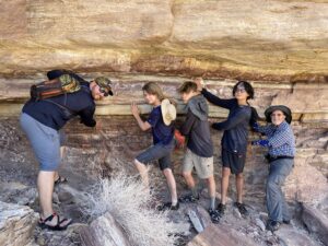Four young men, along with David Losey, place their hands simultaneously on day 3 creation rock and the lowest destruction layer of the Flood.