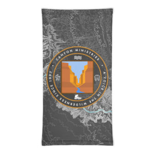 The Neck Gaiter displays a circular canyon, river, and sky logo with the words Canyon Ministries - A Voice in the Wilderness Since 1997 set against a gray topo map backdrop. It makes an excellent match with our River Pillowcase. Explore and shop the Neck Gaiter and River Pillowcase collection!.