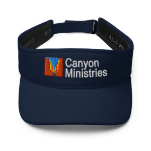 This visor showcases a navy blue hue and is adorned with white Canyon Ministries embroidery. At the front, it also features a vibrant canyon-themed logo.