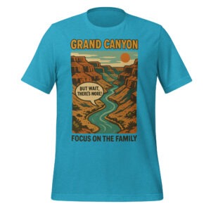 A blue unisex t-shirt featuring a vintage-style Grand Canyon illustration with a river and an orange sun. The words “GRAND CANYON” appear prominently, accompanied by a speech bubble that says, “BUT WAIT, THERE’S MORE!” The phrase “FOCUS ON THE FAMILY” is printed below the main design.