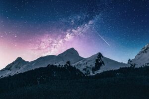 A mountain landscape with the vast starry cosmos visible beyond, illustrating God's creation of the heavens above and the earth below.