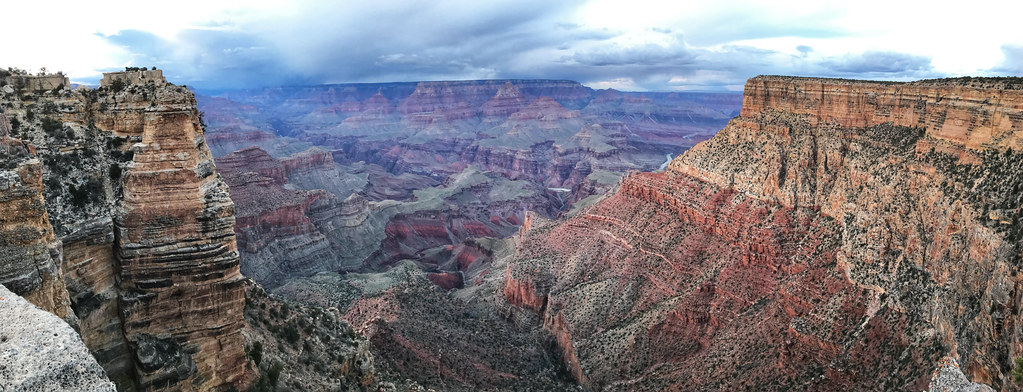 Wide panorama of layered Grand Canyon cliffs beneath gathering storm clouds